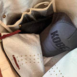 Gray hat with 'Kobe' branding inside a silver bag.