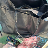 Black handbag on a surface with sunglasses and a magazine underneath